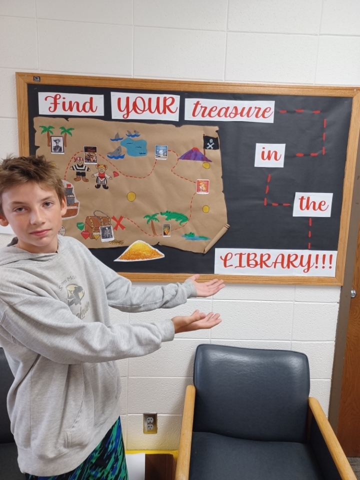student pointing to treasure map bulletin board